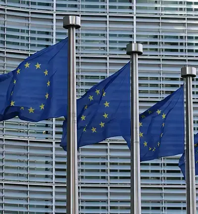 Drei Flaggenmaste mit der europäischen Flagge vor einem Hochhaus