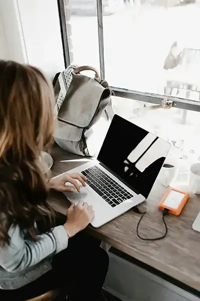 Eine junge Frau sitzt in einem Cafe an einem Laptop und arbeitet
