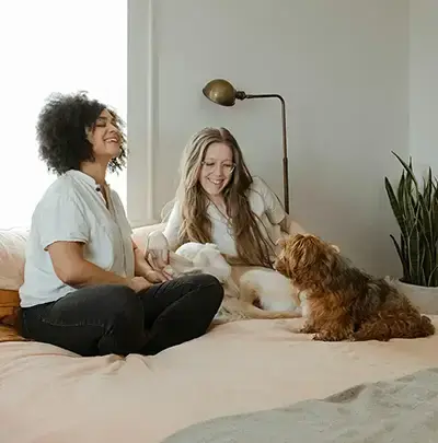 Zwei junge Frauen und ein Hund sitzen auf dem Sofa